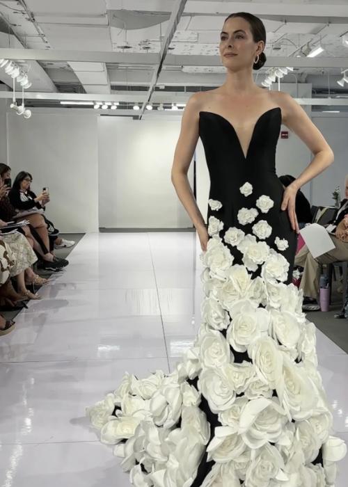 Black strapless mermaid gown with a deep V-neck and cascading white floral appliqués on a satin skirt.