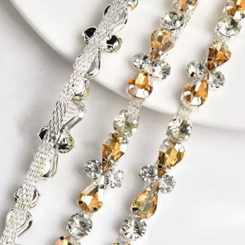 Close-up of intricate silver trim featuring sparkling clear and amber teardrop crystals for an evening gown.