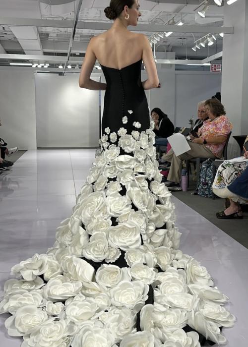 Black strapless mermaid gown with a dramatic train featuring cascading white floral appliqués on a satin fabric.