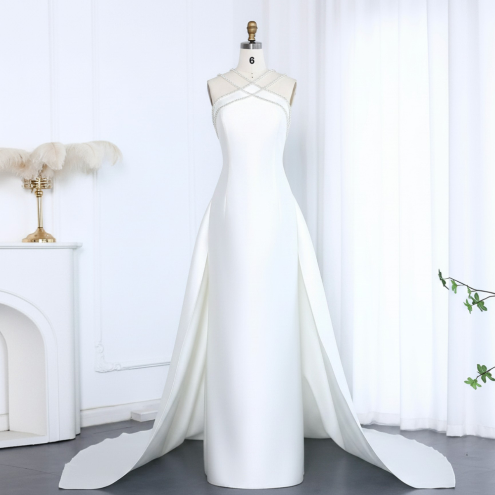 White satin mermaid evening gown with a beaded halter neckline, detachable overskirt, and floor-length train.