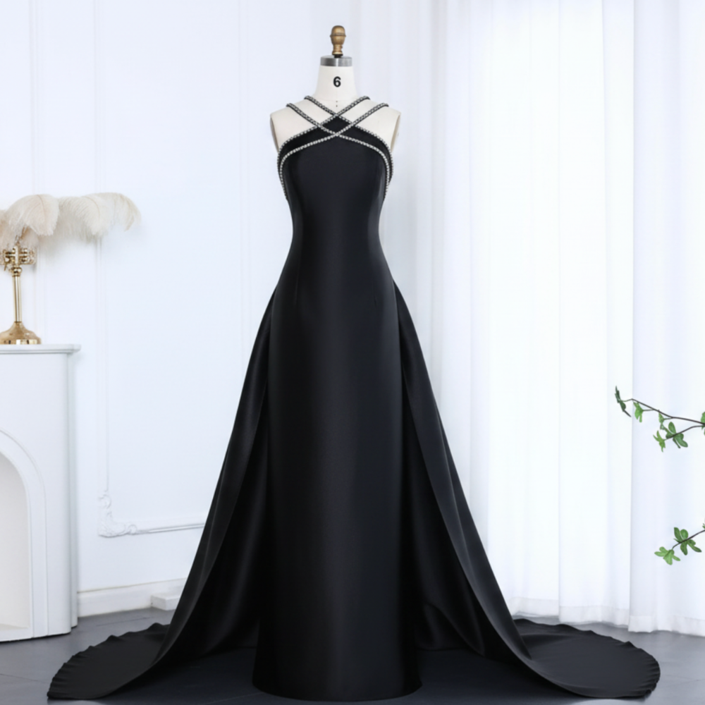 Black satin mermaid evening gown with a crystal-beaded halter neckline and dramatic detachable overskirt train.