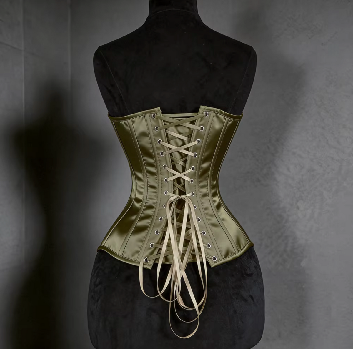 Olive green satin overbust corset with steel boning and a classic lace-up back closure on a black mannequin.