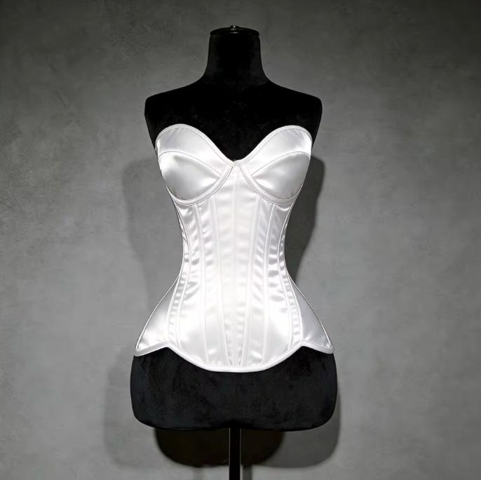 White satin overbust corset with structured cups and steel boning on a black mannequin against a grey background.