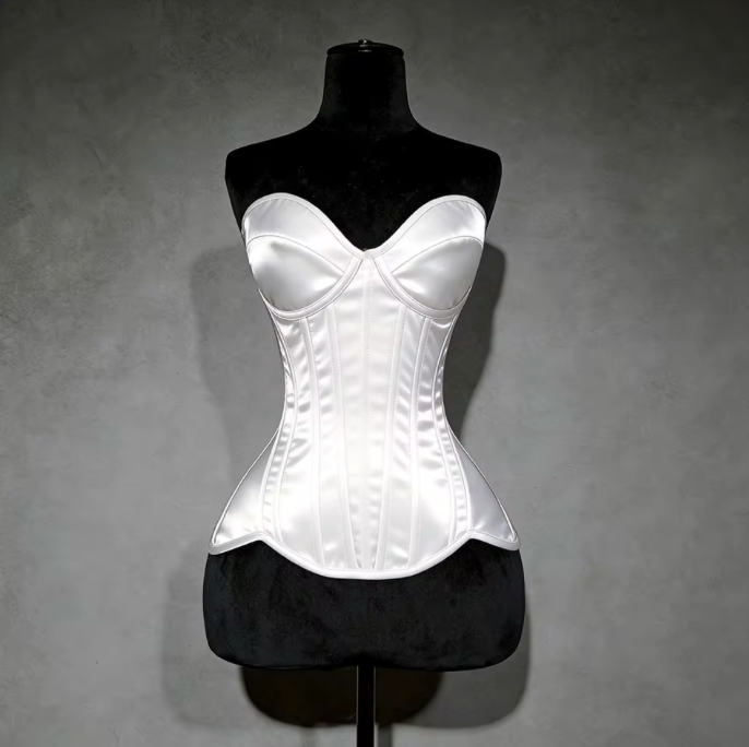White satin overbust corset with structured cups and steel boning on a black mannequin against a grey background.