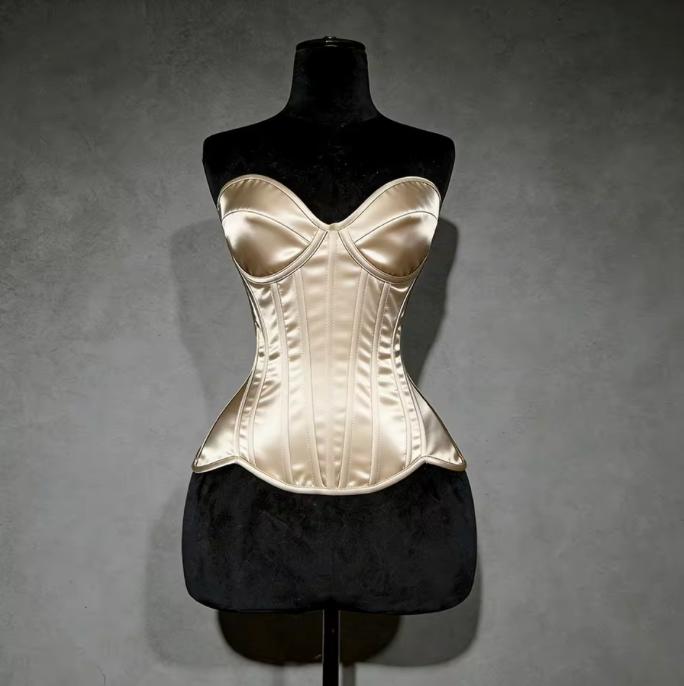 Champagne satin overbust corset with structured cups and steel boning on a black mannequin against a grey background.