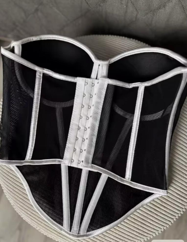 Black mesh corset bustier with white structured piping and a front hook-and-eye closure.