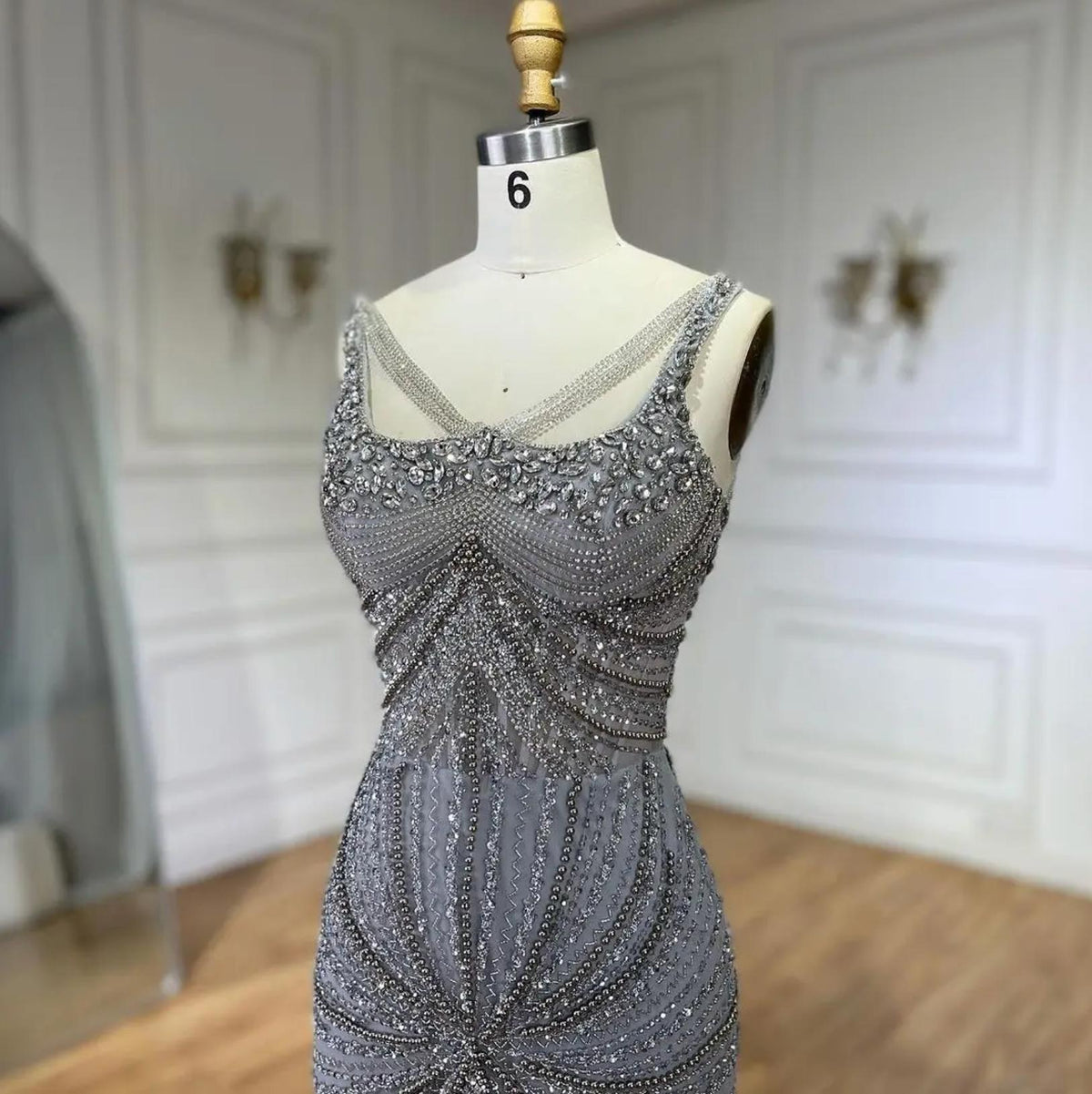 Nude mermaid gown with square neckline, spaghetti straps, and intricate hand-beaded crystal and sequin embellishments.