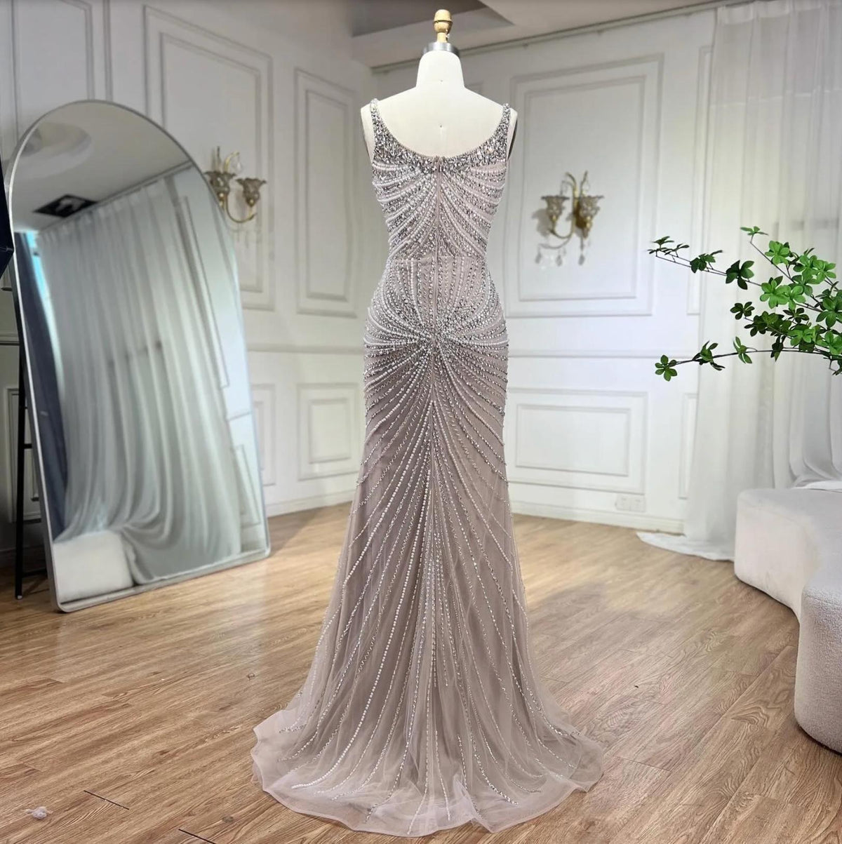 Nude mermaid gown with square neckline, spaghetti straps, and intricate crystal and sequin beadwork on tulle.