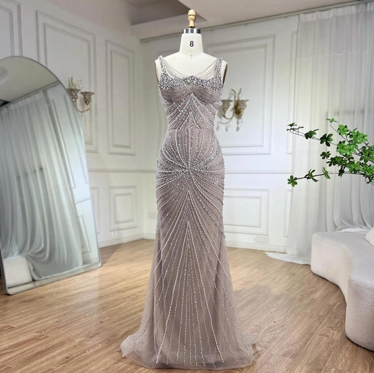 Nude mermaid gown with square neckline, spaghetti straps, and intricate crystal and sequin beadwork on tulle.