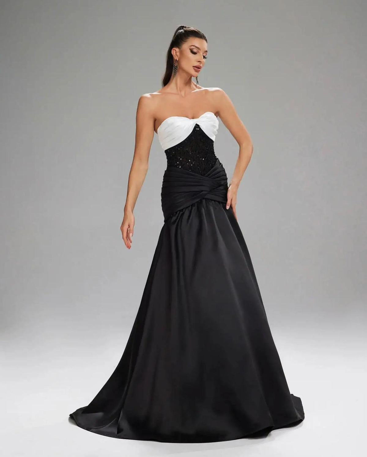 Basra mermaid evening gown with a white sweetheart bodice, black sequined waist, and pleated satin floor-length skirt.