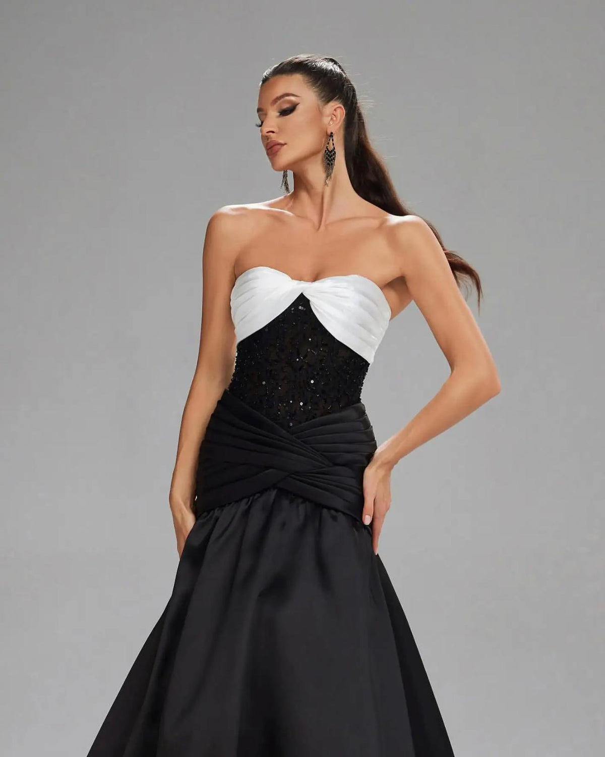 Basra mermaid evening gown featuring a white sweetheart bodice, black sequined waist, and pleated satin skirt.