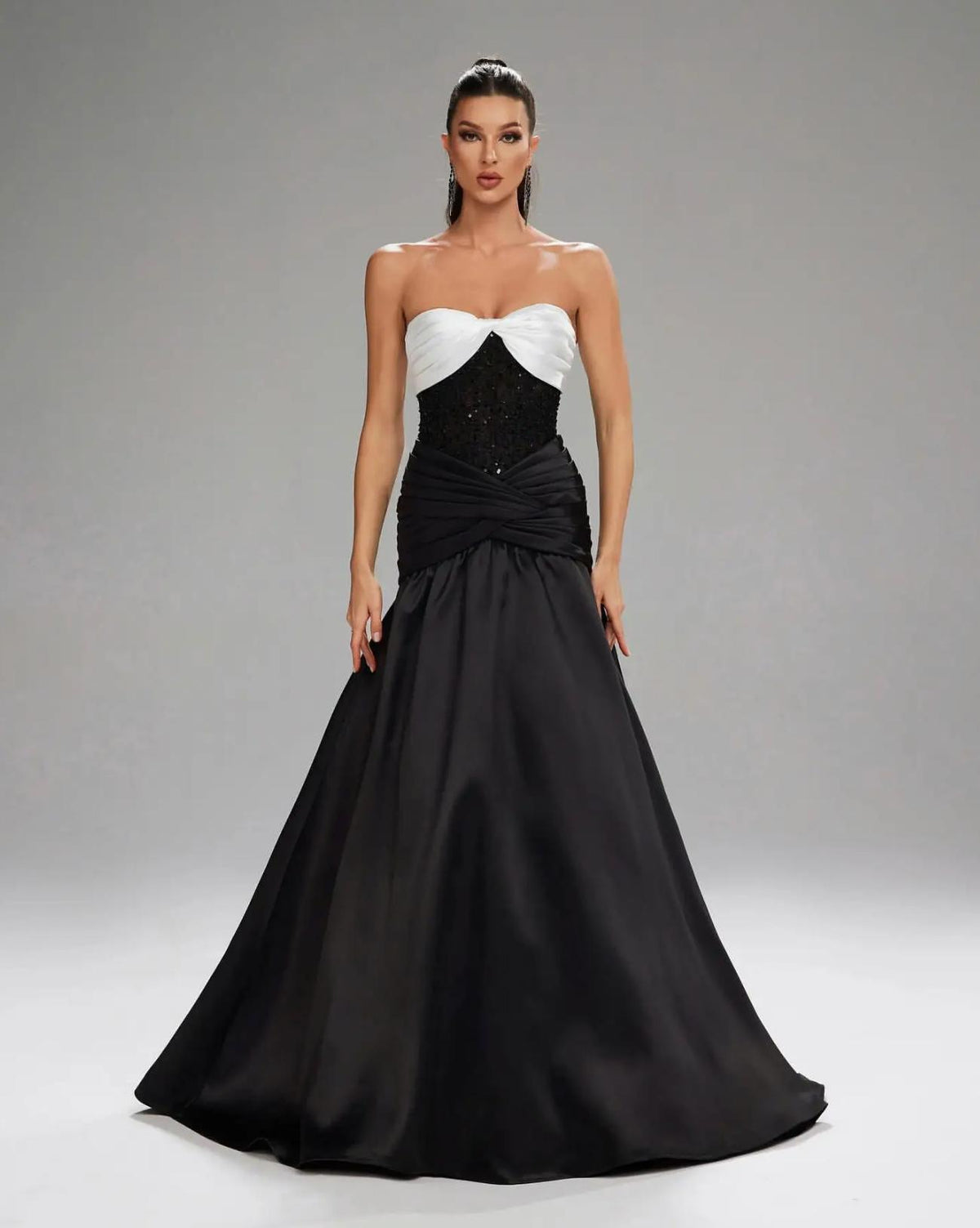 Basra mermaid evening gown featuring a white sweetheart bodice, black sequined waist, and elegant satin pleated skirt.