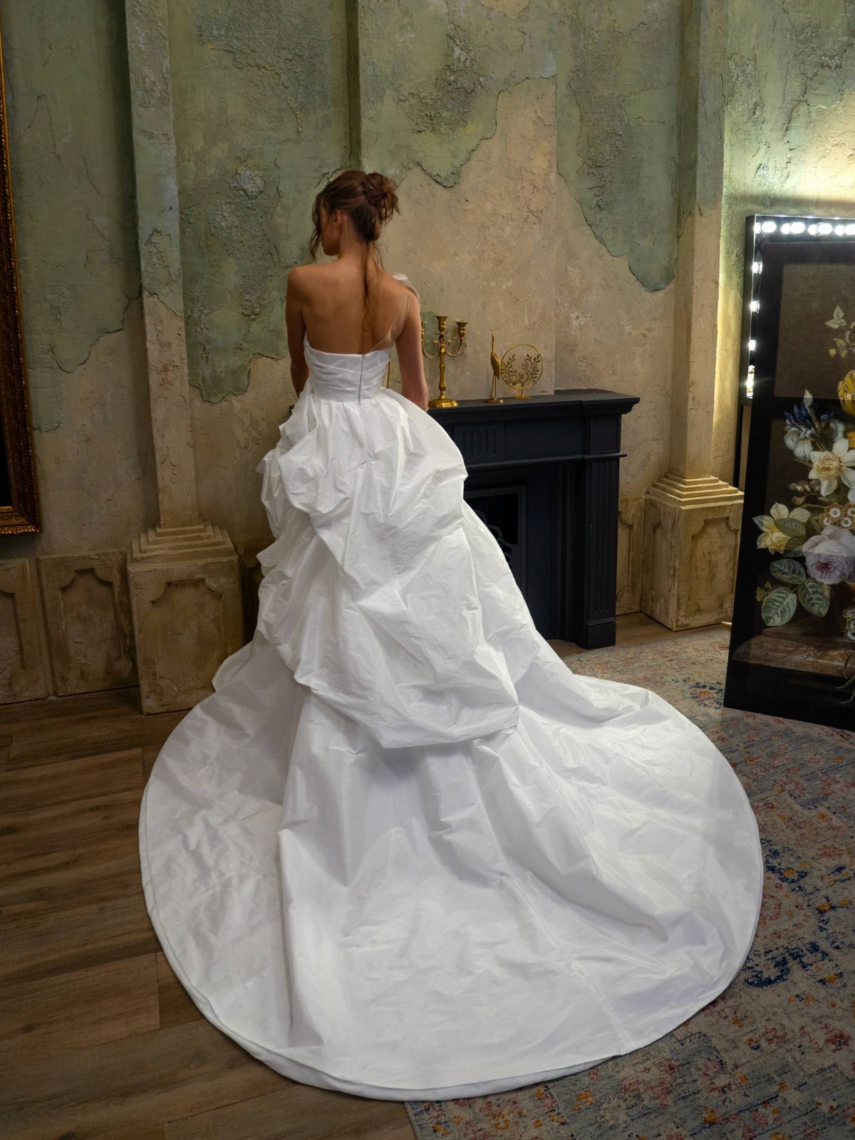 Back view of a white one-shoulder taffeta ball gown with a voluminous, structured skirt and dramatic train.