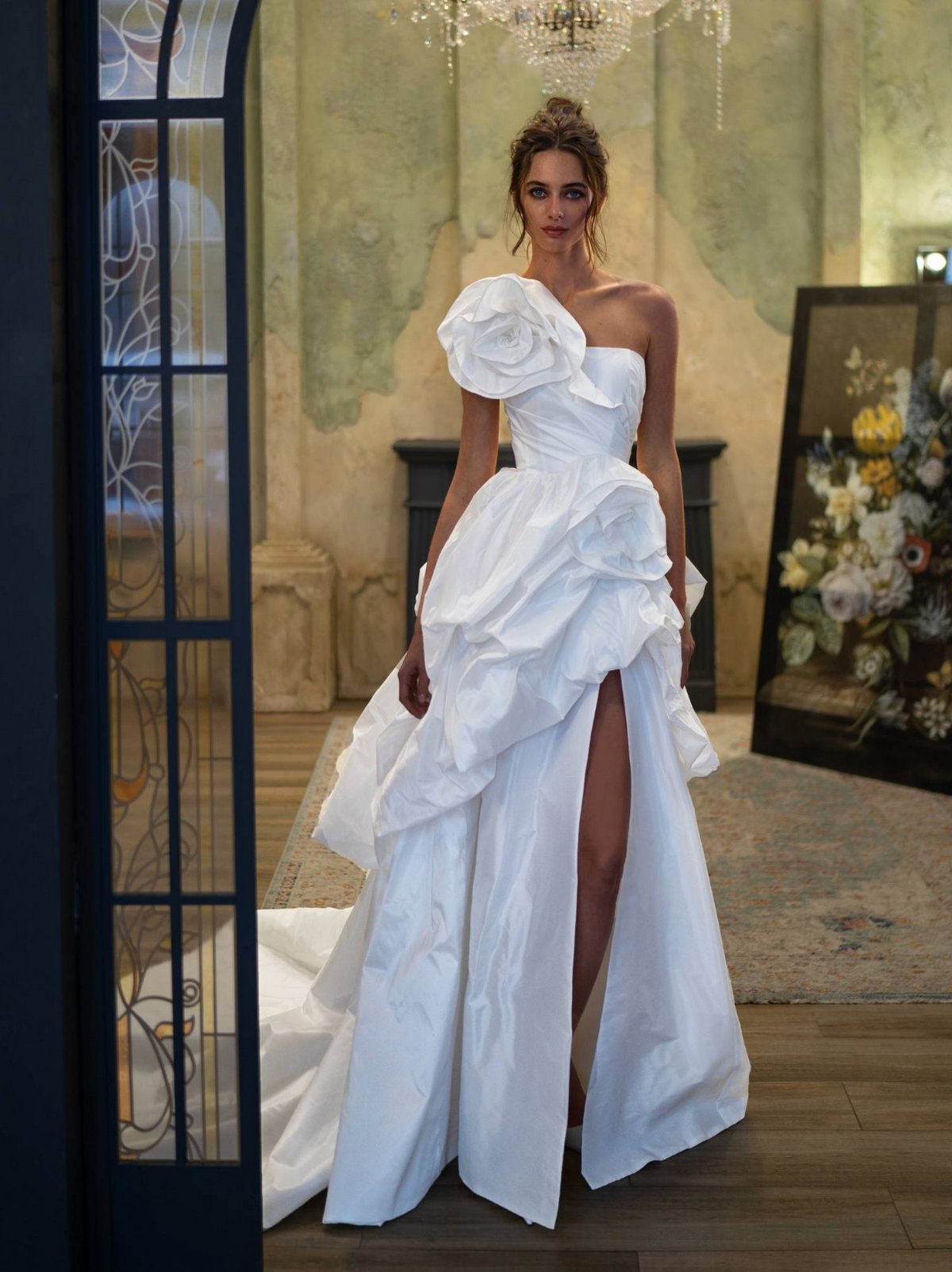 White one-shoulder taffeta ball gown with dimensional floral bodice, voluminous skirt, and high side slit.