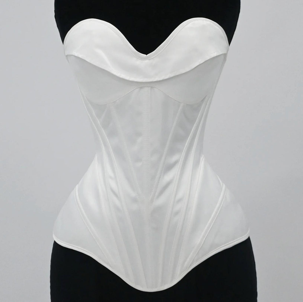 White satin bridal corset bustier with structured boning and a sweetheart neckline on a black mannequin.