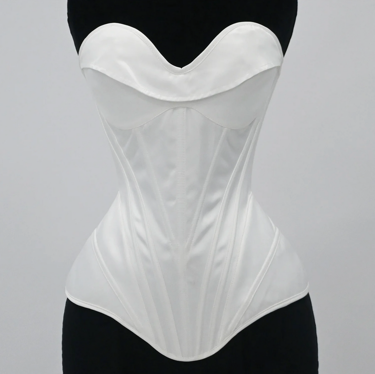 White satin bridal corset bustier with structured boning and a sweetheart neckline on a black mannequin.