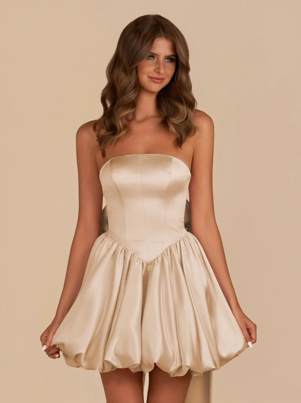 Champagne satin mini dress with a strapless corset bodice, voluminous skirt, and a large detachable back bow.