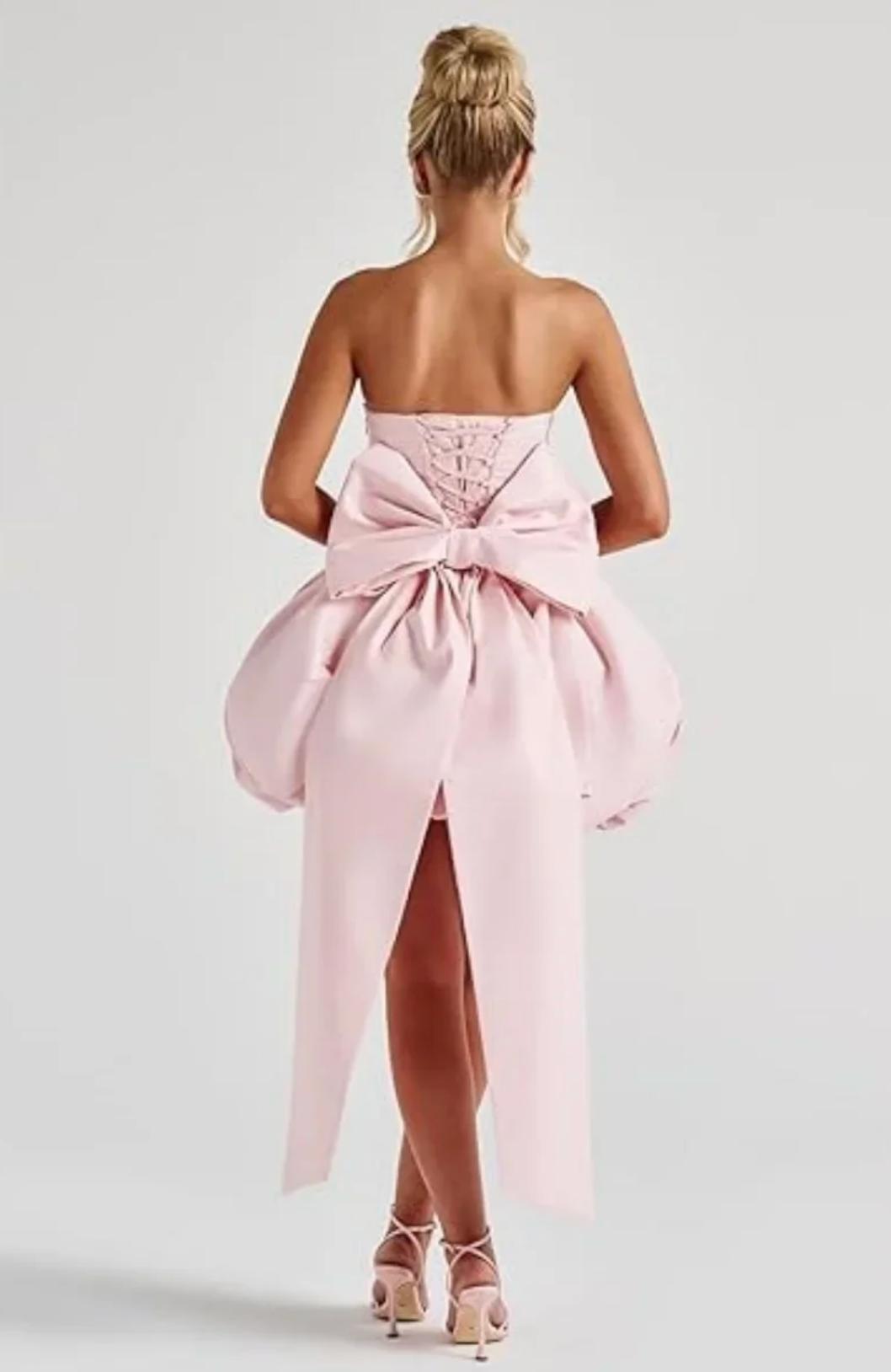Back view of a pink satin mini dress with a corset lace-up back and a large detachable statement bow.
