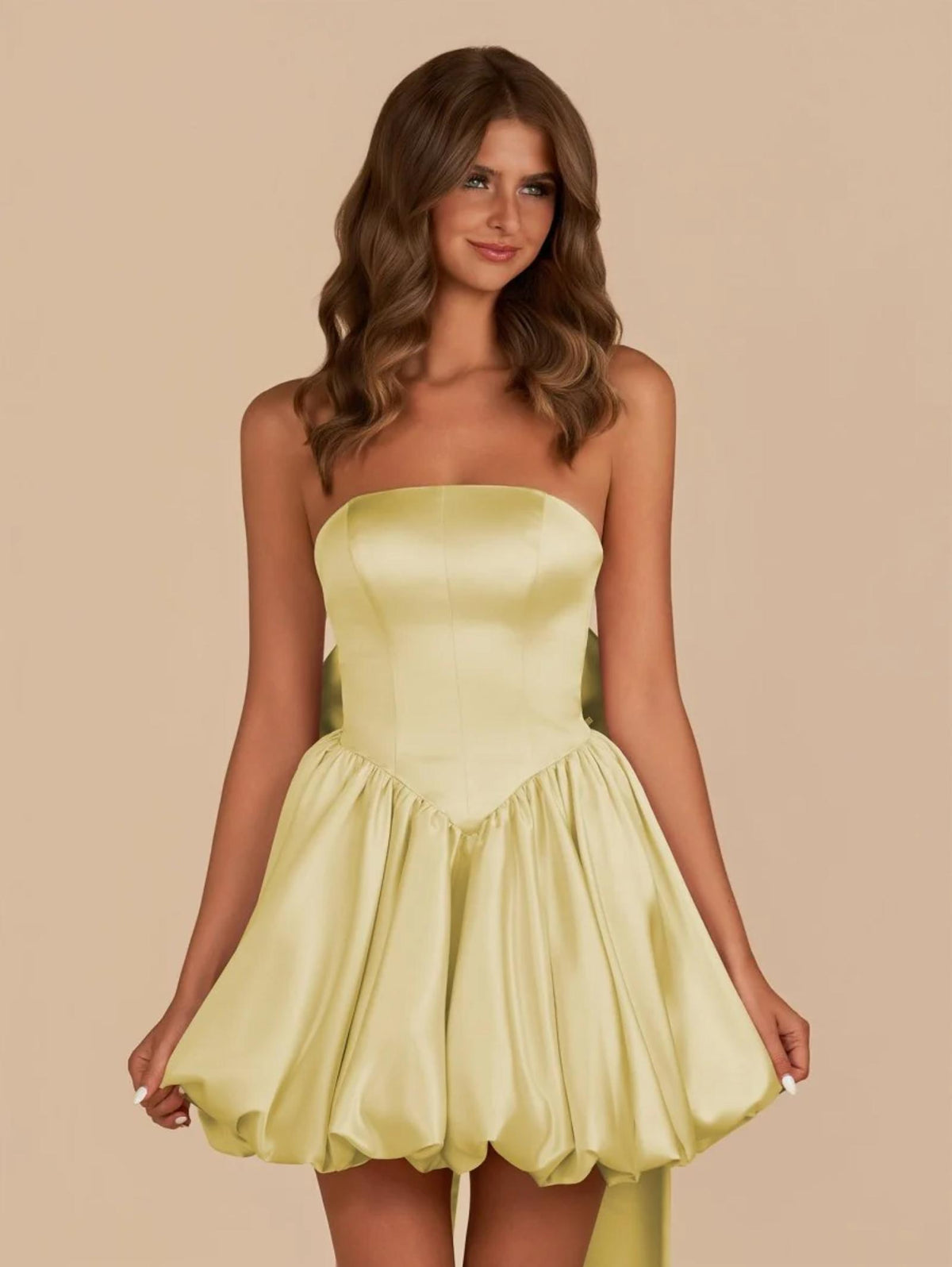 Strapless pale yellow satin mini dress with a structured bodice and voluminous skirt featuring a detachable back bow.