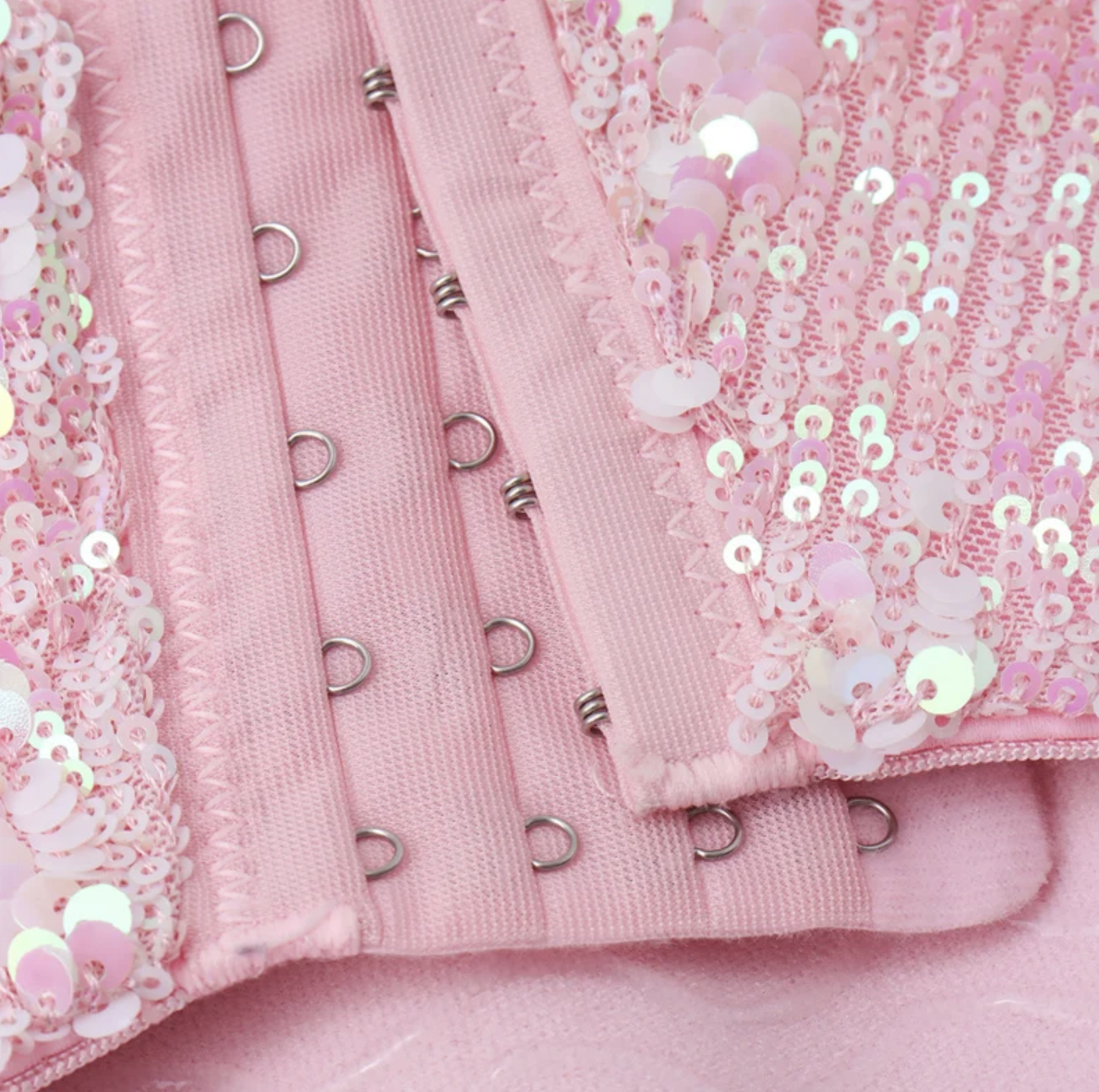 Pink handmade corset bustier featuring shimmering iridescent sequins and a secure metal hook-and-eye front closure.
