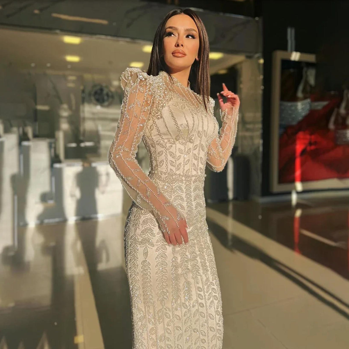 Beaded mermaid gown with intricate pearl and crystal embroidery on sheer tulle, featuring long sleeves and a fitted silhouette.