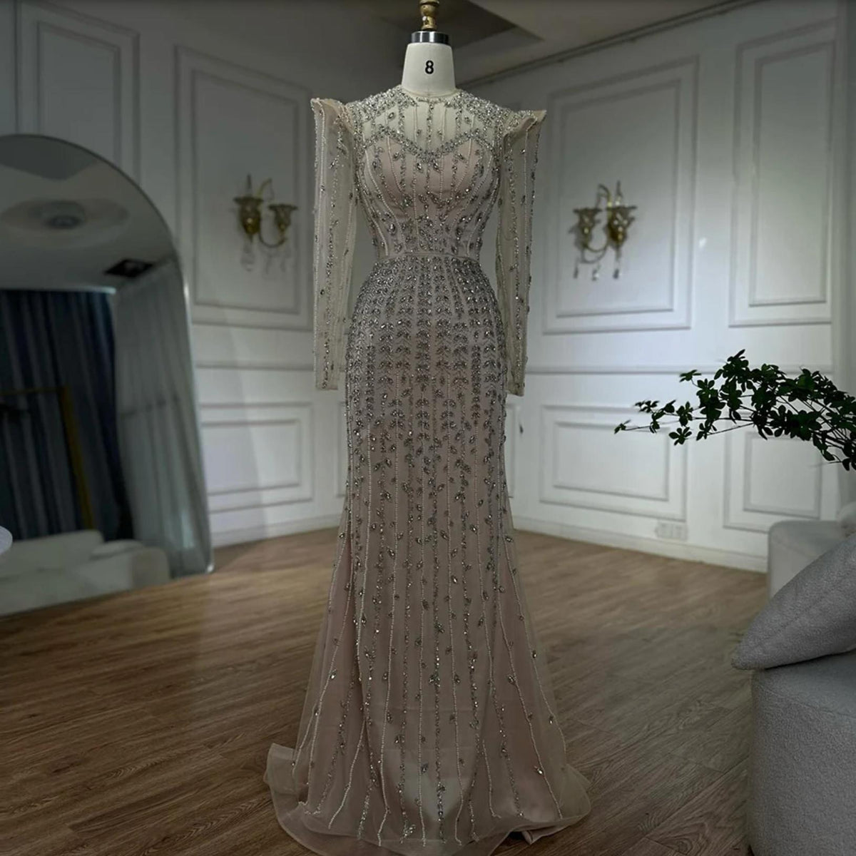 Beige mermaid gown with long sleeves, intricate crystal beading, and pearl embellishments on a size 8 mannequin.
