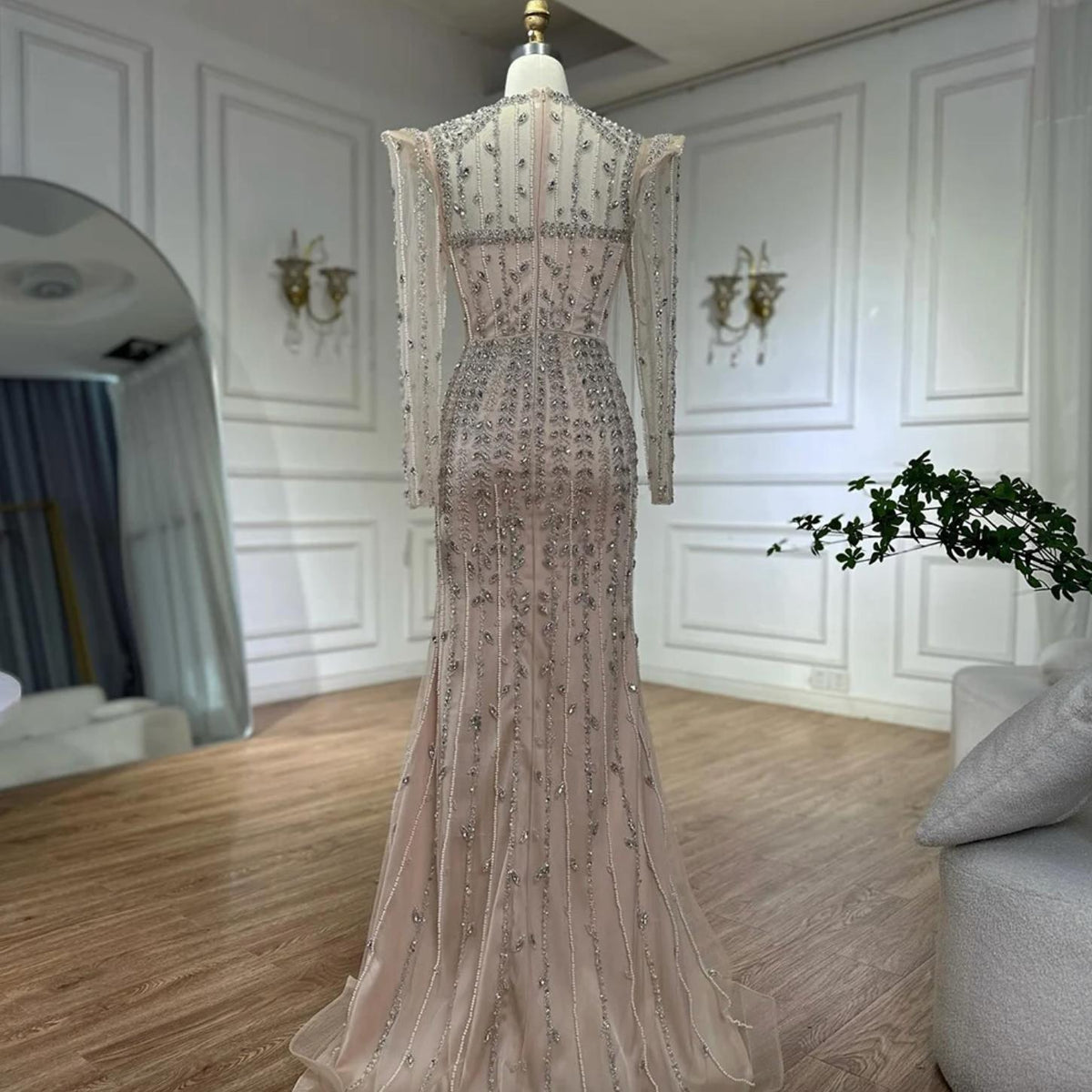 Beige mermaid gown featuring intricate silver beading, crystals, and pearl embellishments on soft tulle with long sleeves.