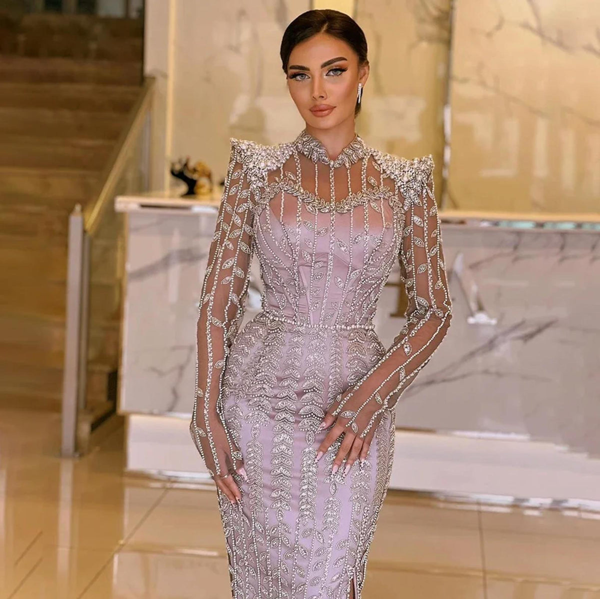 Lavender mermaid gown with intricate crystal beading, pearl accents, long sheer sleeves, and a high neck.