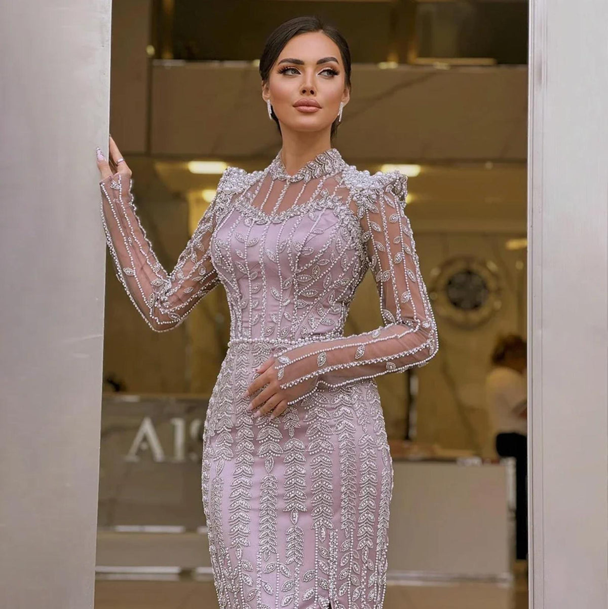 Lavender mermaid gown featuring intricate silver beading, pearl embellishments, long sheer sleeves, and a high o-neck.