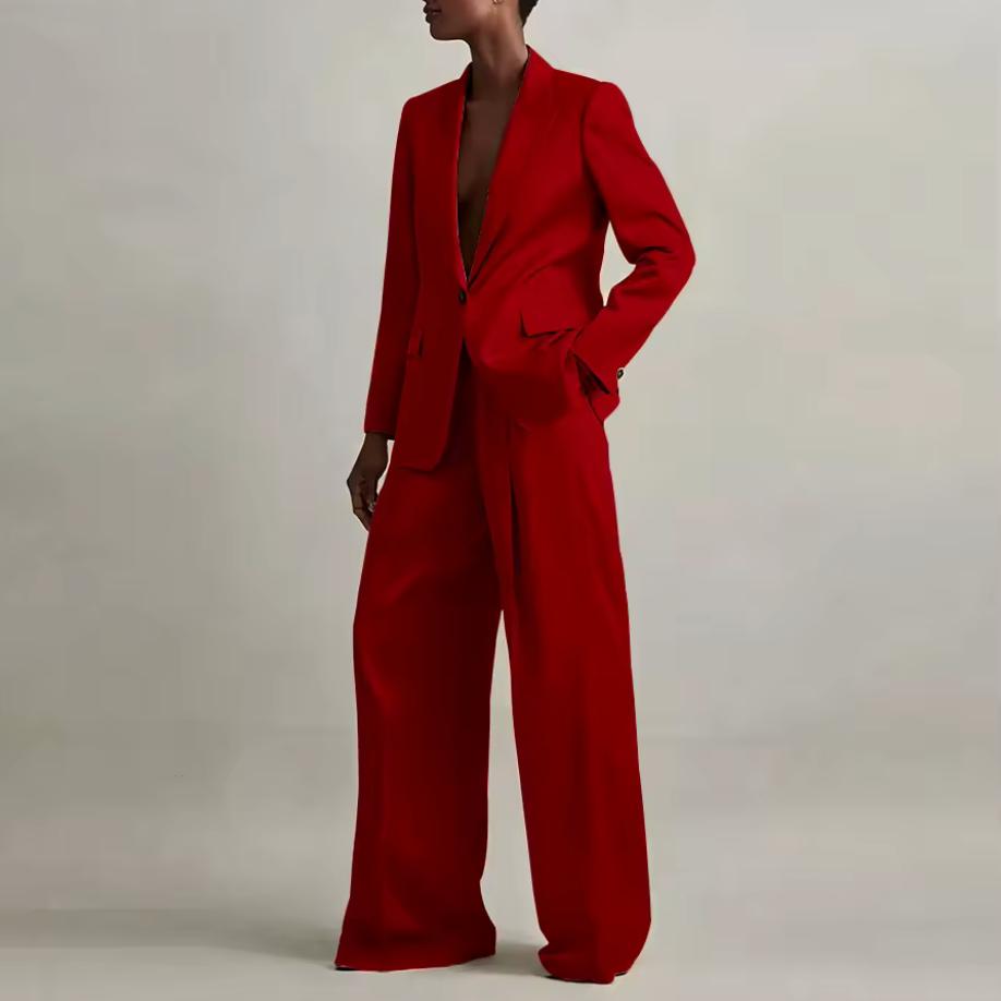 Model wearing a vibrant red silk pant suit with a tailored single-button blazer and wide-leg trousers.