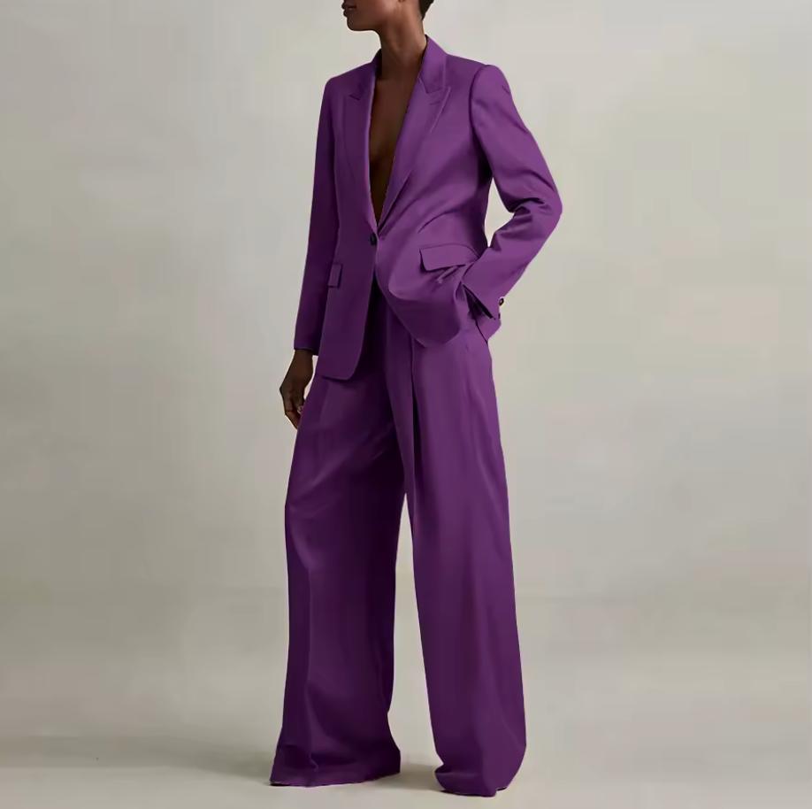 Model wearing a vibrant purple silk pant suit with a tailored single-button blazer and wide-leg trousers.