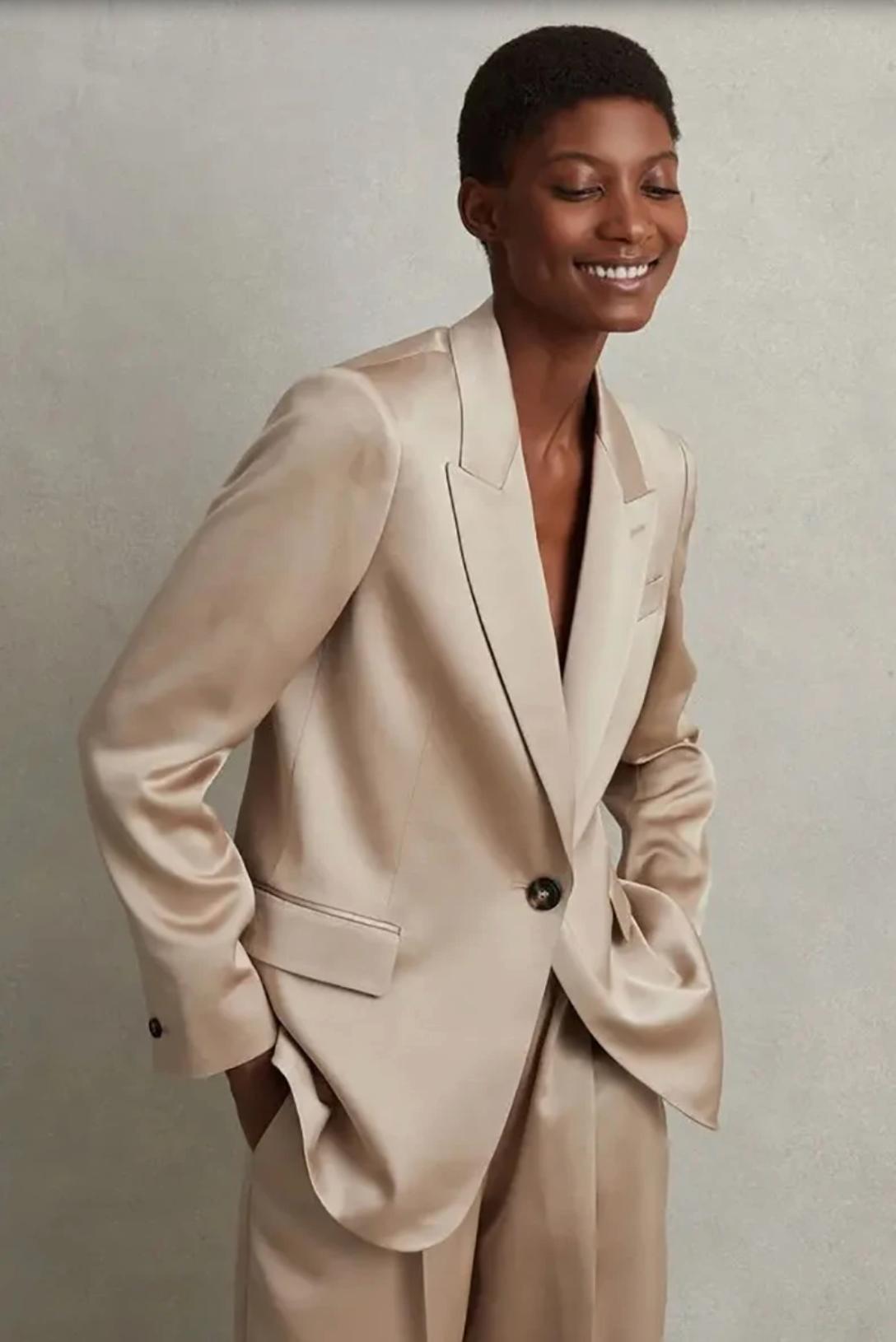 Model wearing a champagne-colored silk satin pant suit with an oversized single-button blazer and wide-leg trousers.