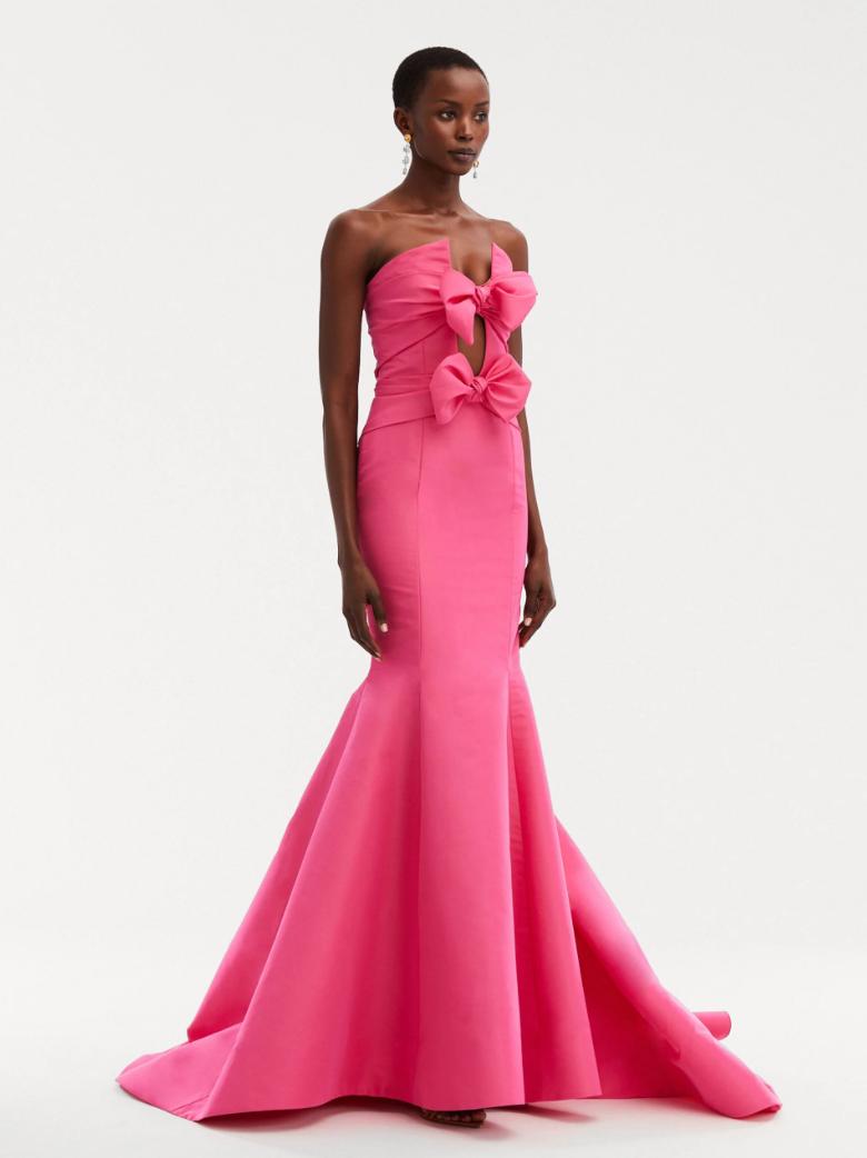 Hot pink silk faille mermaid ballgown with a plunging split neckline, bow adornments, and a floor-sweeping fluted skirt.