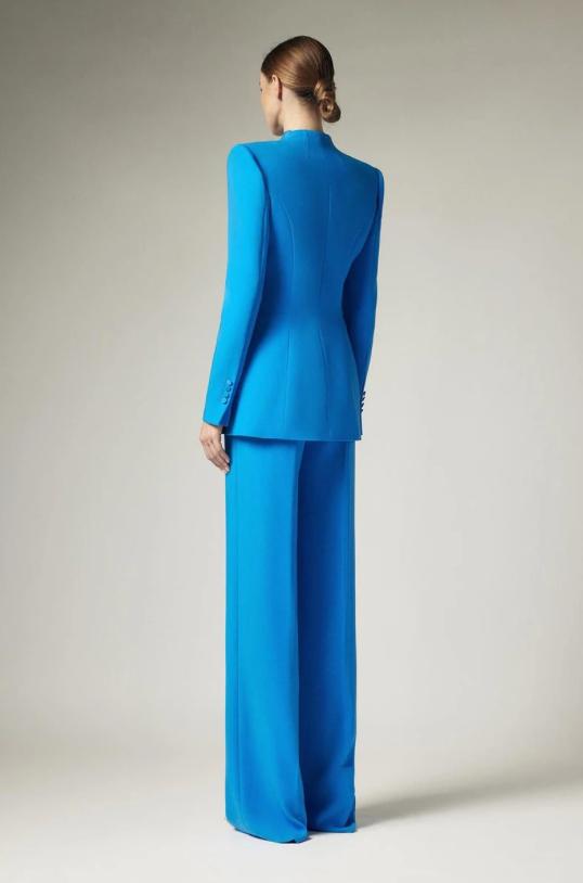 Woman wearing a vibrant blue two-piece business suit with a tailored single-breasted blazer and wide-leg trousers.