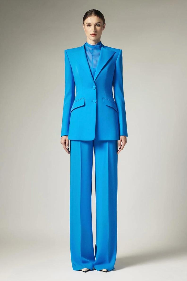 Model wearing a bright blue two-piece business suit with a single-breasted blazer and matching wide-leg trousers.