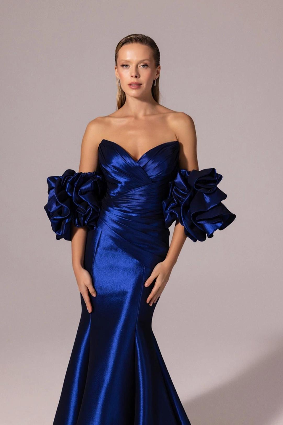 Royal blue satin mermaid gown with off-the-shoulder neckline and dramatic ruffled sleeves.