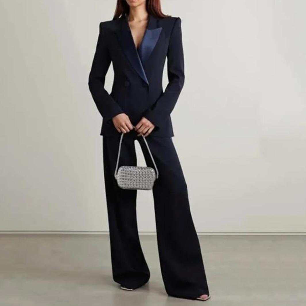 Navy blue Brioni Vanqui double-breasted suit with satin peaked lapels and tailored wide-leg trousers for women.