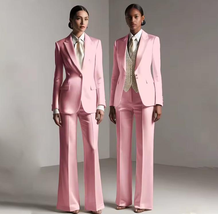 Two models wearing tailored pink satin single-breasted pantsuits with white shirts and formal vests.