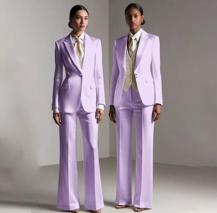 Two models wearing tailored lavender satin single-breasted pantsuits with white shirts and formal vests.
