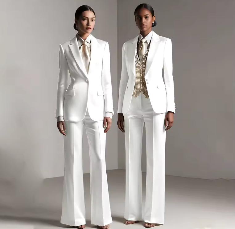 Two models wearing elegant white satin single-breasted pantsuits with tailored jackets and flared trousers.