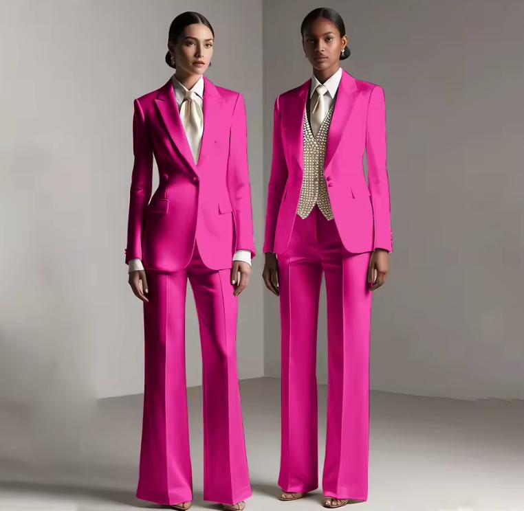 Two models wearing vibrant pink satin single-breasted pantsuits with tailored jackets and coordinating trousers.
