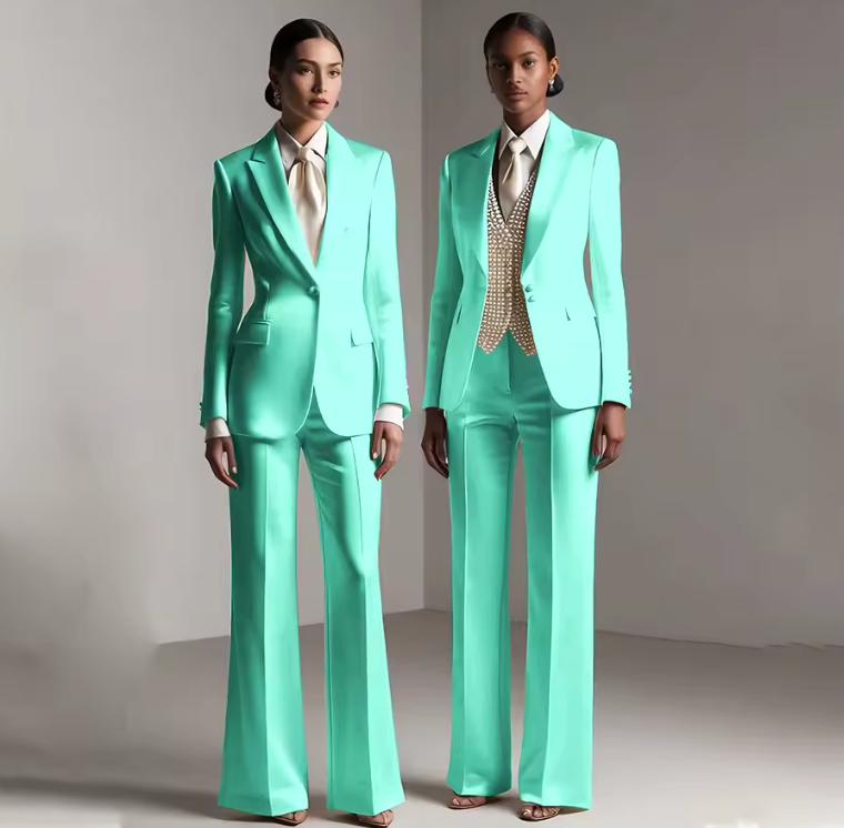 Two models wearing tailored mint green satin single-breasted pantsuits with wide-leg trousers and formal shirts.