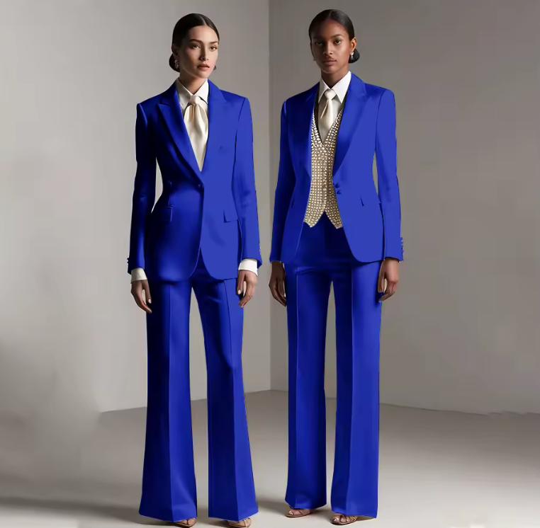 Two models wearing tailored royal blue satin pantsuits with single-breasted jackets and coordinating trousers.