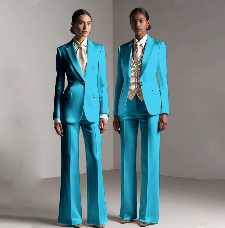 Two models wearing Brisbane satin pantsuits in vibrant turquoise with tailored jackets and coordinating trousers.