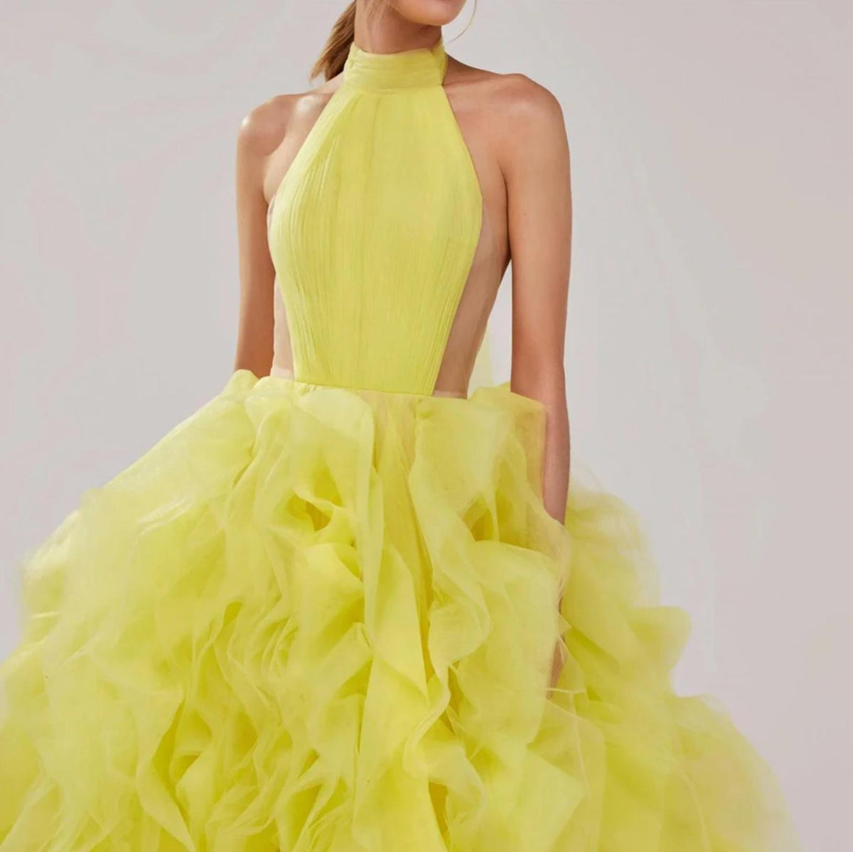 Bright yellow halter ball gown featuring a pleated bodice and voluminous, tiered tulle skirt.