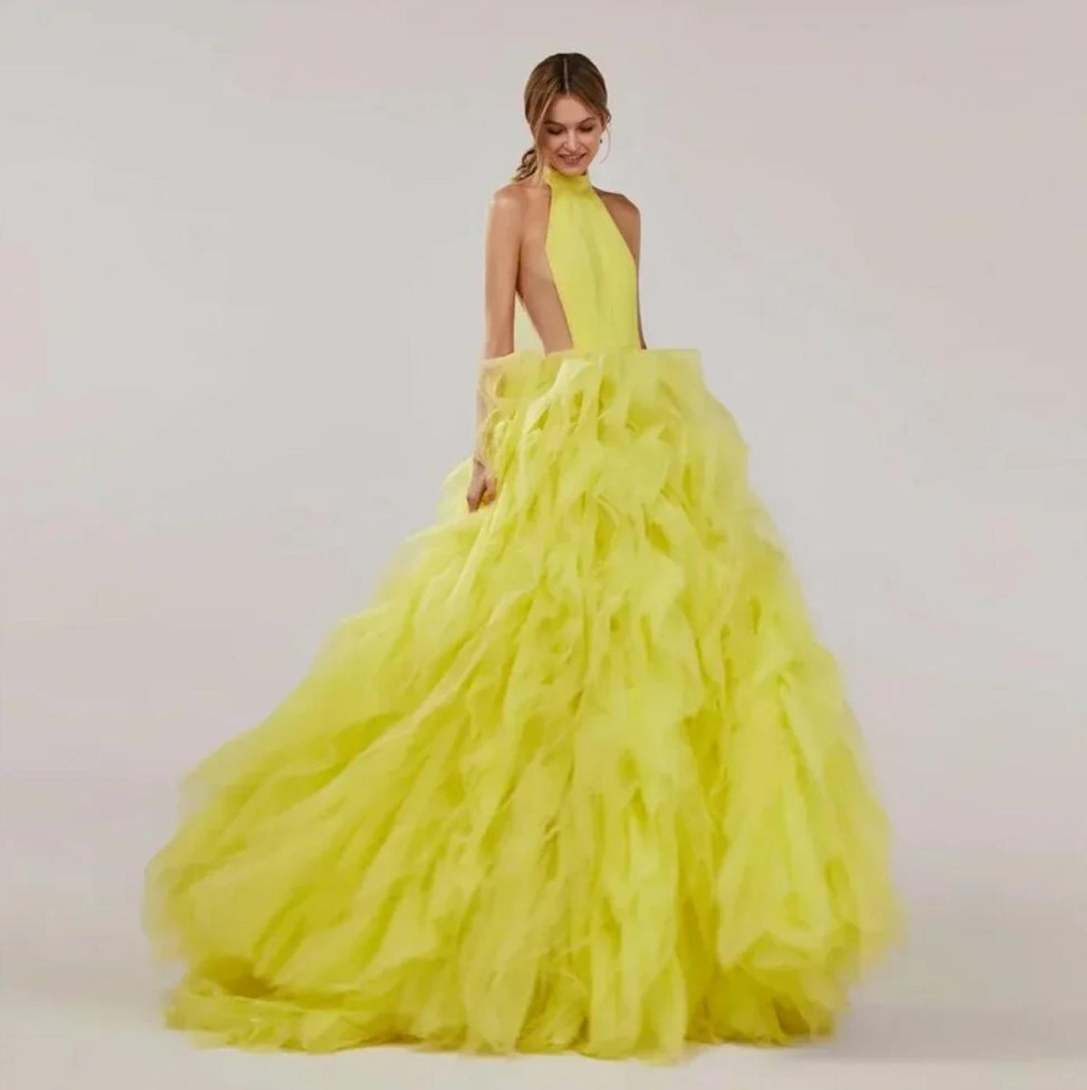 Bright yellow halter ball gown with tiered tulle pleating, a sleeveless bodice, and a dramatic floor-sweeping skirt.