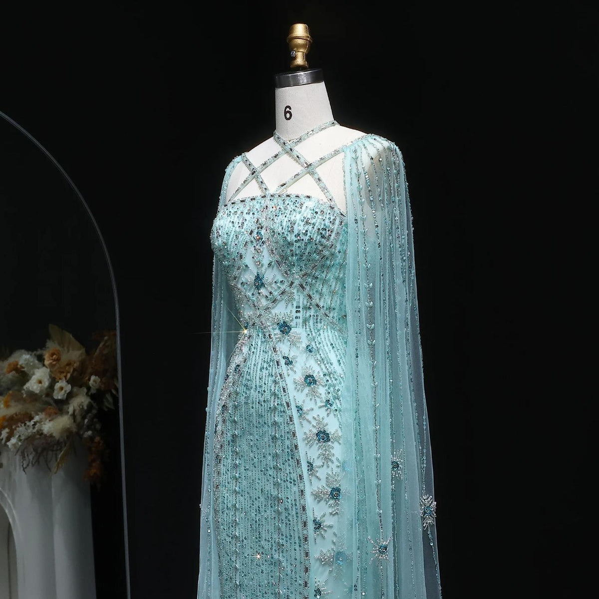 Light blue mermaid gown with cape sleeves, criss-cross neckline, and intricate crystal and sequin beadwork.