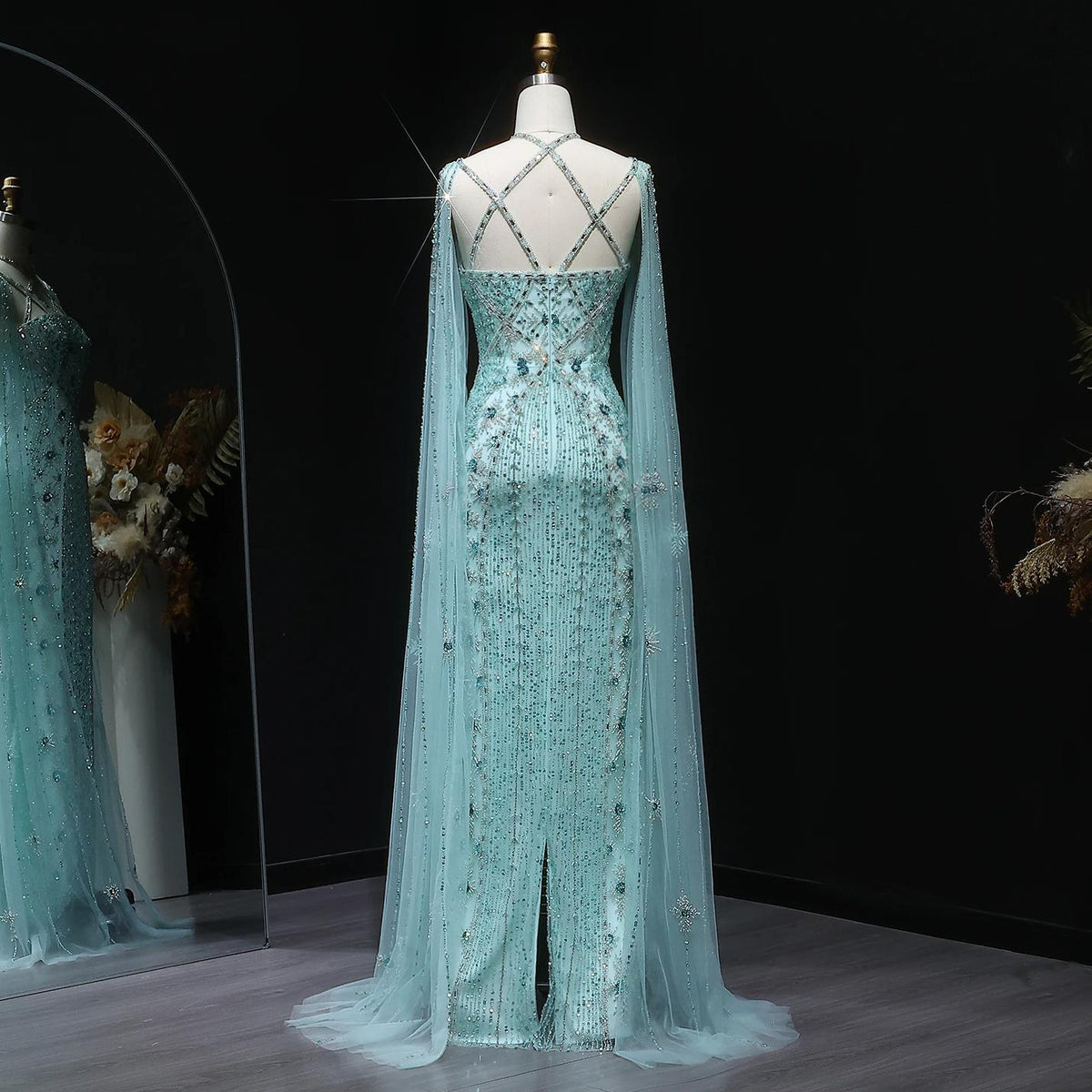 Back view of a light blue mermaid gown with cape sleeves, criss-cross straps, and intricate crystal and sequin beading.