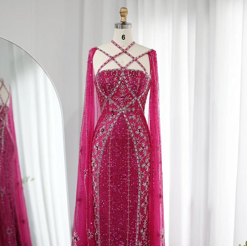Magenta mermaid gown with cape sleeves, criss-cross neckline, and intricate crystal and sequin beadwork on a mannequin.