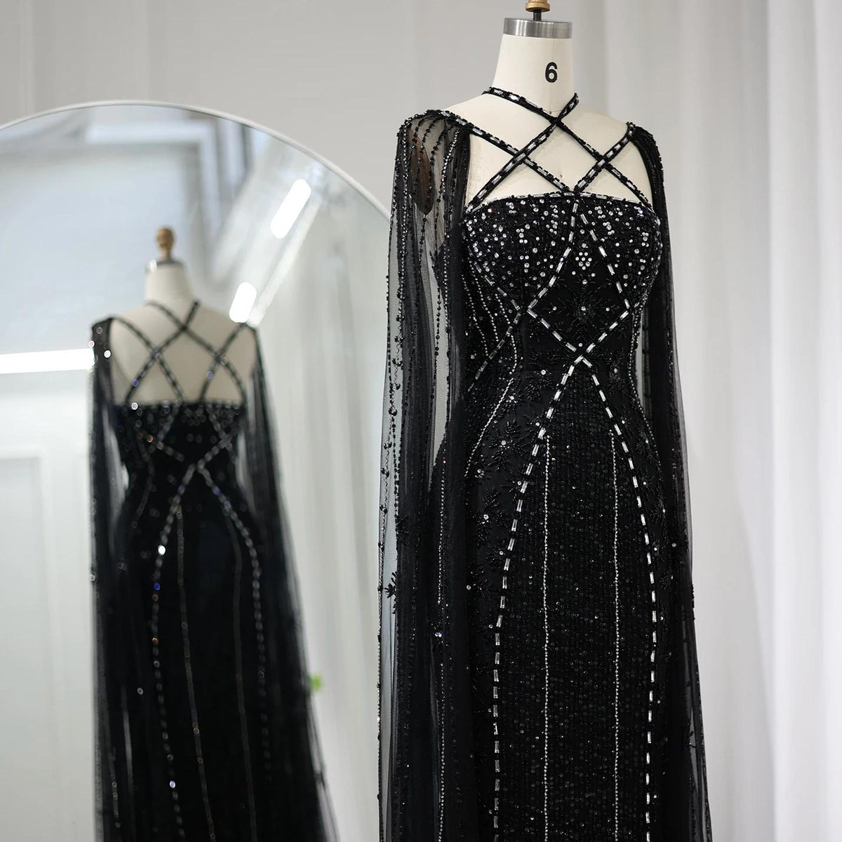 Black mermaid gown with tulle cape sleeves, criss-cross neckline, and intricate crystal and sequin embellishments.
